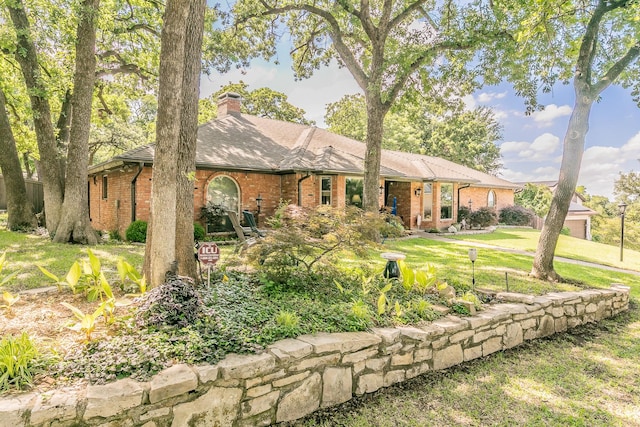 view of front of home featuring brick siding, a chimney, a front lawn, and an attached garage