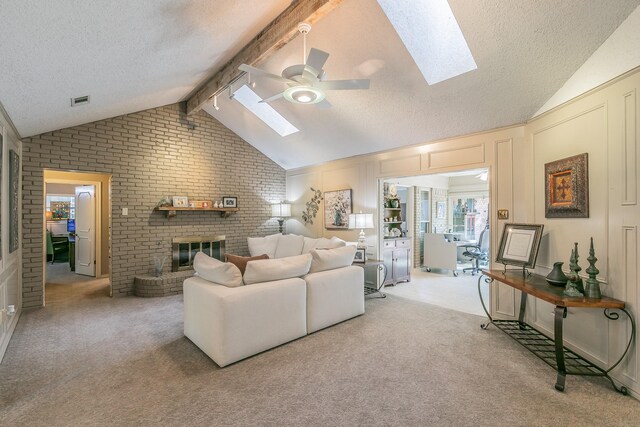 living room with a skylight, a ceiling fan, a textured ceiling, a fireplace, and brick wall