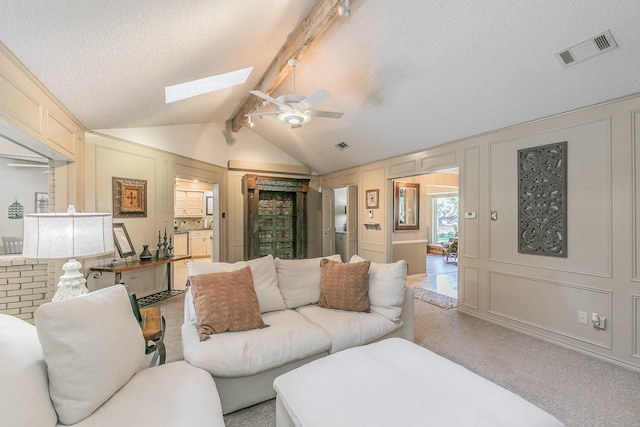living room featuring a decorative wall, a skylight, a textured ceiling, and ceiling fan