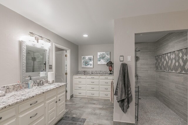 bathroom featuring tiled shower, vanity, wood finished floors, and recessed lighting