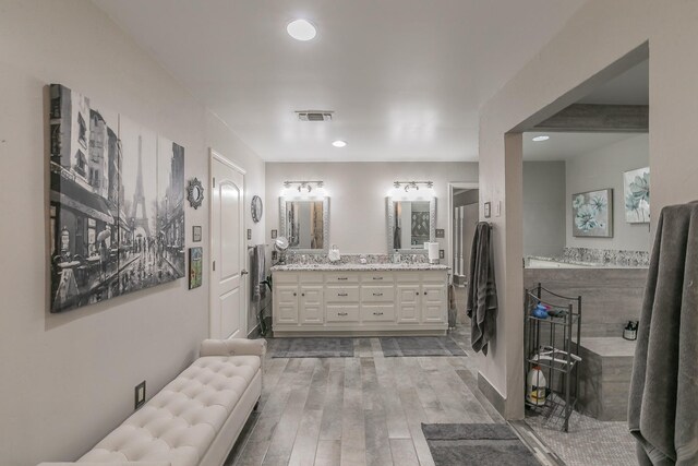 full bathroom featuring wood finished floors, double vanity, and recessed lighting