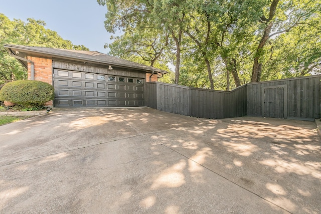 garage with driveway, fence, and a gate