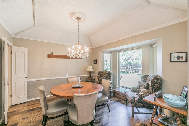 dining space with wood finished floors, ornamental molding, a chandelier, and vaulted ceiling