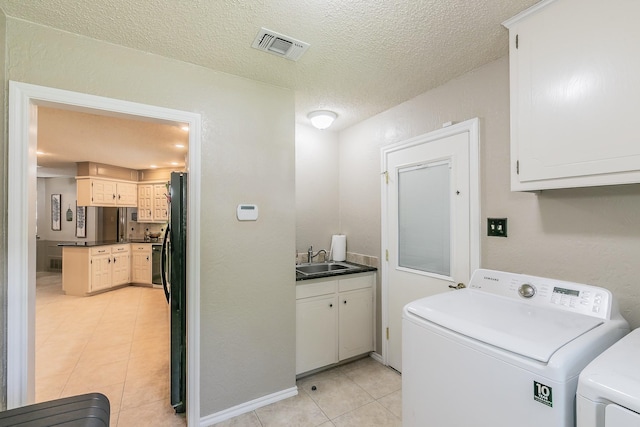 laundry area with cabinet space, washing machine and clothes dryer, light tile patterned floors, and a textured ceiling