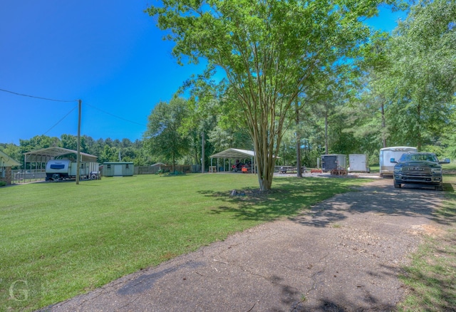 451 Burney St, Coushatta, LA 71019 - view of grassy yard featuring a detached carport, a storage shed, driveway, and an outdoor structure