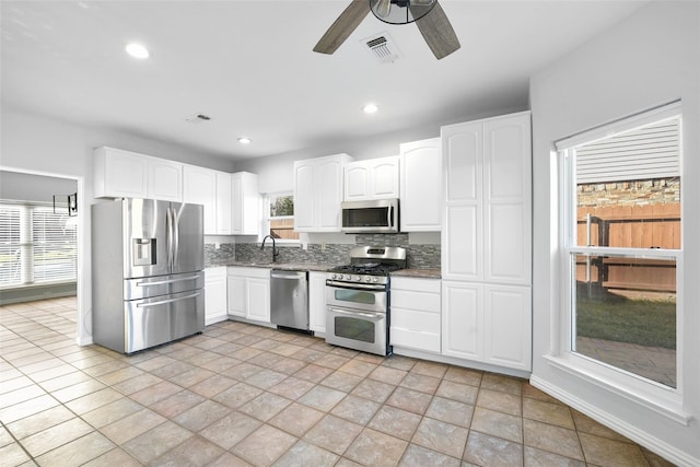 1315 Falcon Dr, Lewisville, TX 75077 - kitchen with appliances with stainless steel finishes, a sink, white cabinetry, decorative backsplash, and ceiling fan