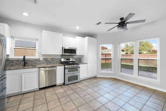 1315 Falcon Dr, Lewisville, TX 75077 - kitchen featuring appliances with stainless steel finishes, a sink, dark stone countertops, decorative backsplash, and ceiling fan
