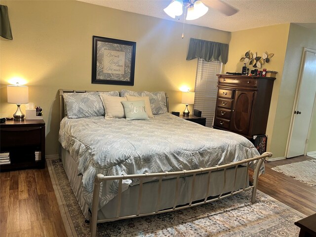 bedroom with wood finished floors, baseboards, and a textured ceiling