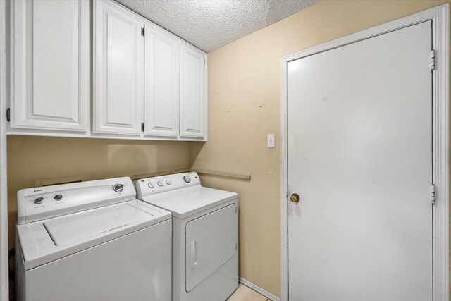 clothes washing area featuring washing machine and clothes dryer, cabinet space, and a textured ceiling