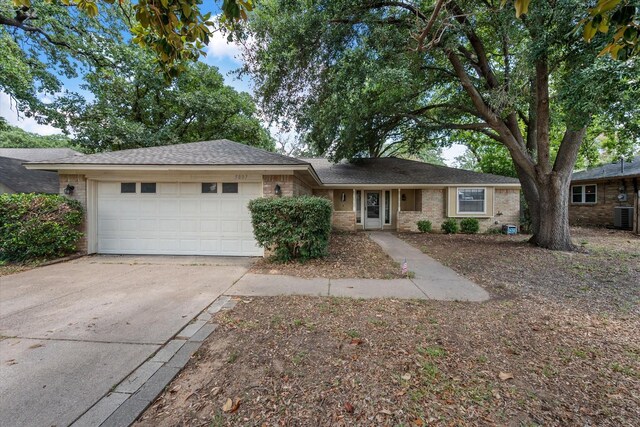 ranch-style home featuring a garage, driveway, brick siding, and central AC