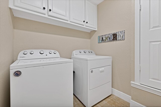 clothes washing area with washer and clothes dryer, cabinet space, and baseboards