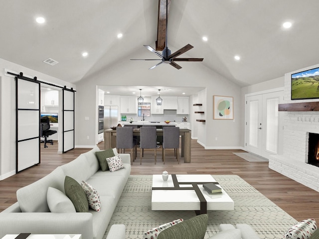309 Rash Ln, Terrell, TX 75160 - living area featuring a barn door, a fireplace, light wood-style floors, beam ceiling, and a ceiling fan