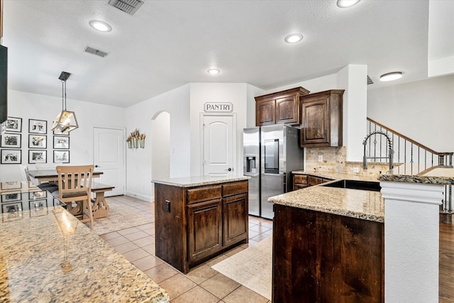 6273 El Capitan St, Fort Worth, TX 76179 - kitchen featuring stainless steel refrigerator with ice dispenser, backsplash, dark brown cabinetry, a peninsula, and a sink