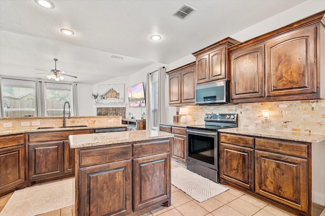 6273 El Capitan St, Fort Worth, TX 76179 - kitchen with stainless steel appliances, a sink, tasteful backsplash, light stone counters, and a ceiling fan