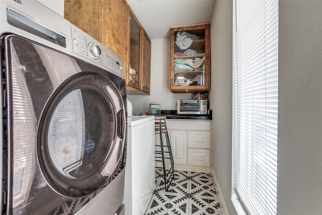 clothes washing area featuring cabinet space, washer and dryer, and light tile patterned floors