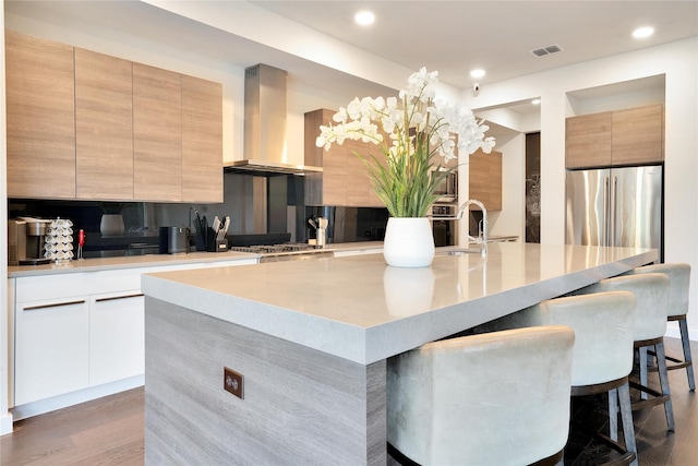3520 Valmur Ave, Colleyville, TX 76034 - kitchen with wall chimney range hood, a sink, freestanding refrigerator, modern cabinets, and a breakfast bar