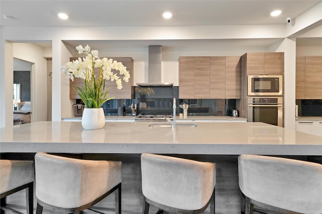 3520 Valmur Ave, Colleyville, TX 76034 - kitchen featuring appliances with stainless steel finishes, wall chimney exhaust hood, modern cabinets, a sink, and a breakfast bar