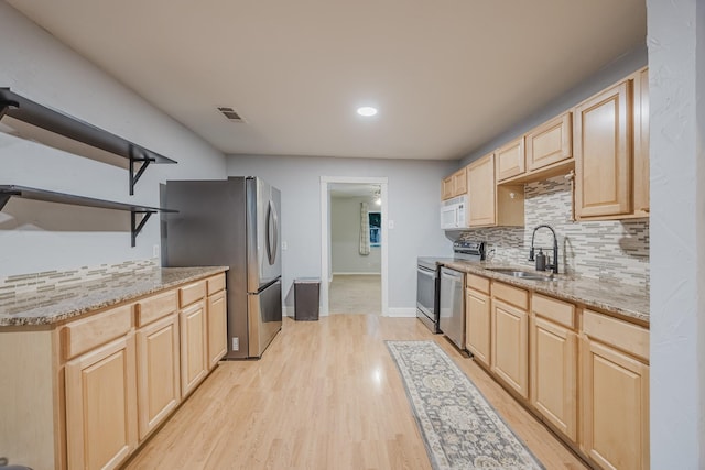 kitchen with a sink, light brown cabinetry, appliances with stainless steel finishes, open shelves, and decorative backsplash