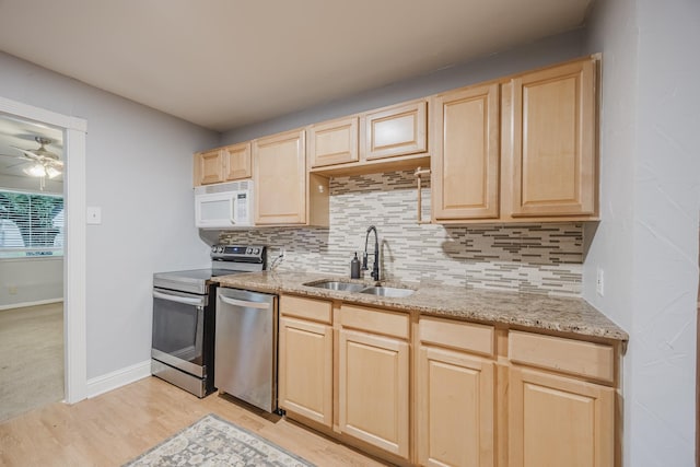 kitchen featuring light brown cabinets, a sink, stainless steel appliances, and backsplash