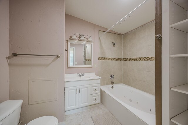 bathroom with toilet, a combined bath / shower with jetted tub, vanity, and tile patterned flooring