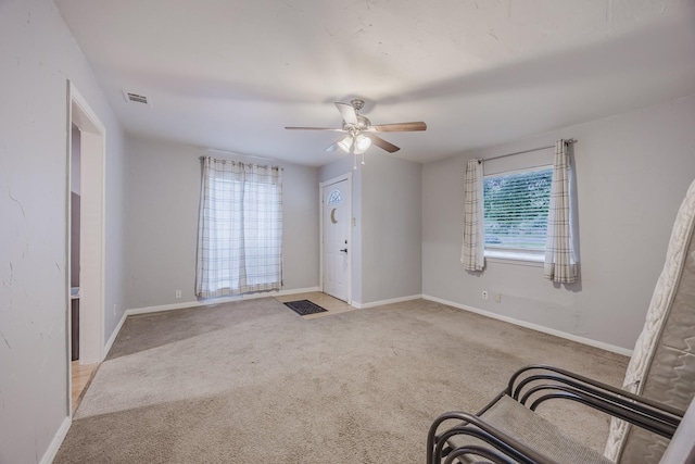 carpeted foyer with a ceiling fan and baseboards