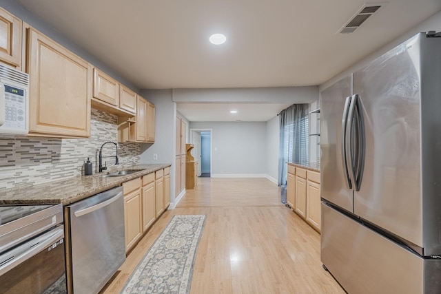 kitchen featuring stainless steel appliances, light brown cabinets, a sink, and recessed lighting
