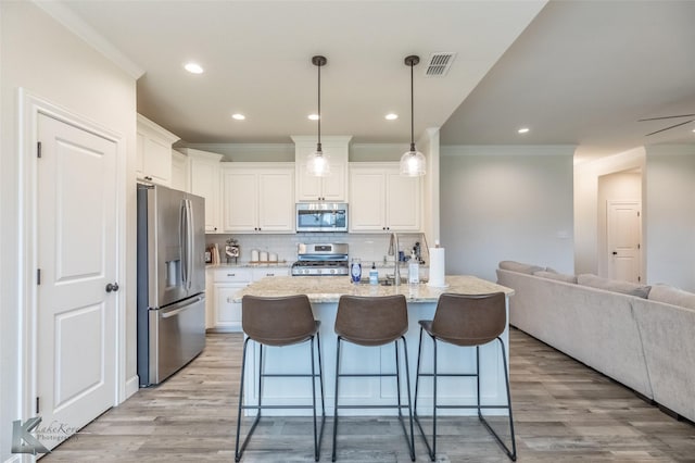 kitchen featuring appliances with stainless steel finishes, ornamental molding, open floor plan, white cabinetry, and light wood finished floors