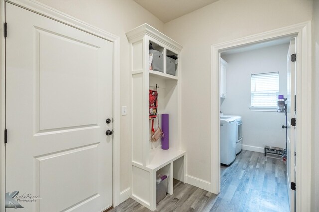 mudroom featuring washing machine and clothes dryer, light wood finished floors, and baseboards