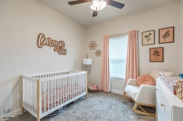 bedroom with a nursery area, carpet, a ceiling fan, and baseboards