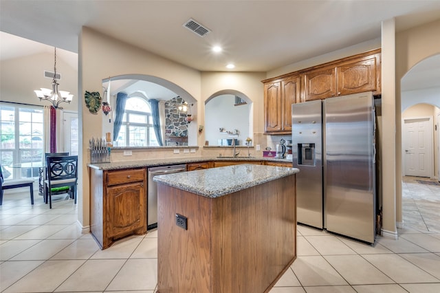 314 Trakehner Trl, Celina, TX 75009 - kitchen featuring stainless steel appliances, a sink, a center island, brown cabinetry, and light tile patterned flooring