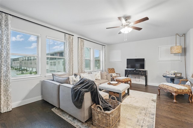living room with dark wood-style flooring, a ceiling fan, and baseboards