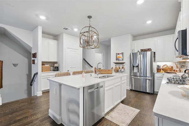 kitchen with stainless steel appliances, a sink, backsplash, an island with sink, and light countertops