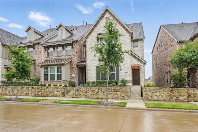 view of front of property with stone siding, a shingled roof, and brick siding