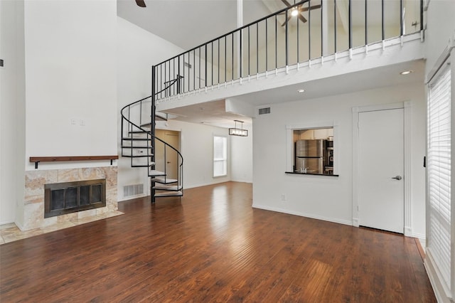 9826 Bent Branch Ln, Dallas, TX 75243 - unfurnished living room featuring a high ceiling, wood finished floors, stairs, a fireplace, and ceiling fan
