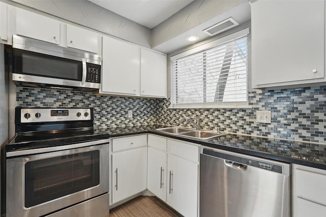 9826 Bent Branch Ln, Dallas, TX 75243 - kitchen with stainless steel appliances, dark countertops, tasteful backsplash, white cabinets, and light wood-style flooring