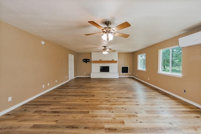 1941 State Highway 59 S, Bowie, TX 76230 - unfurnished living room featuring a ceiling fan, a wall mounted air conditioner, wood finished floors, baseboards, and a large fireplace