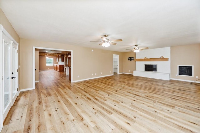 1941 State Highway 59 S, Bowie, TX 76230 - unfurnished living room with a fireplace, light wood-style floors, a ceiling fan, and baseboards