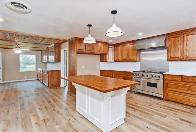 1941 State Highway 59 S, Bowie, TX 76230 - kitchen with double oven range, wall chimney exhaust hood, brown cabinets, wood counters, and light wood-style floors