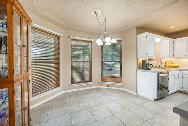 unfurnished dining area featuring a sink, light tile patterned floors, a textured ceiling, a chandelier, and baseboards