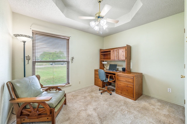 home office with a textured ceiling, light carpet, a ceiling fan, and baseboards