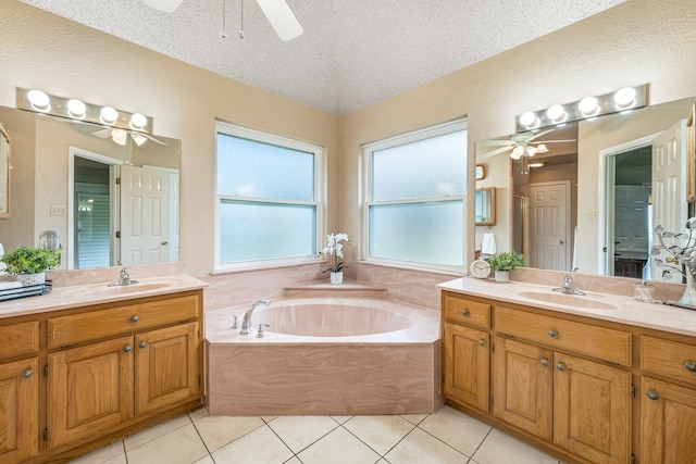 bathroom with ceiling fan, two vanities, a bath, and a textured ceiling