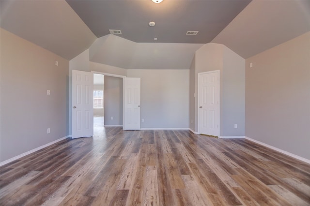 empty room featuring vaulted ceiling, baseboards, and wood finished floors