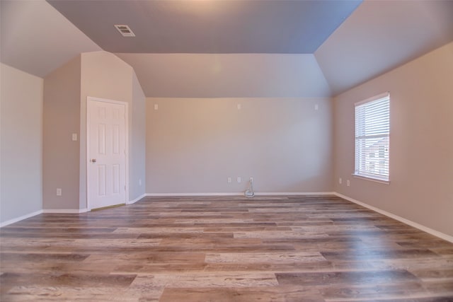 spare room featuring vaulted ceiling, baseboards, and wood finished floors