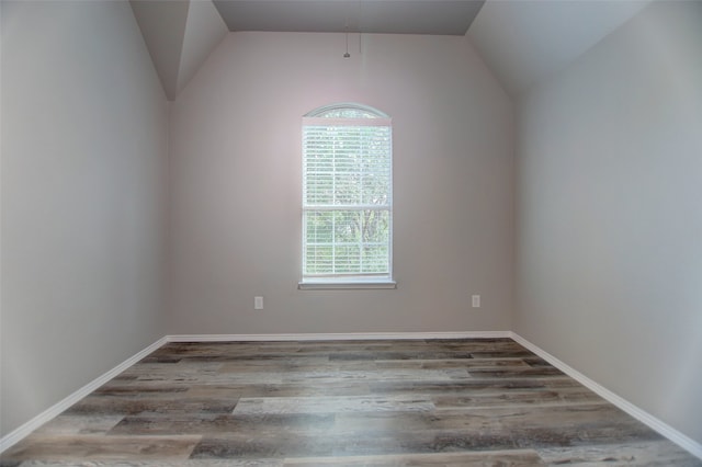 empty room with vaulted ceiling, wood finished floors, and baseboards