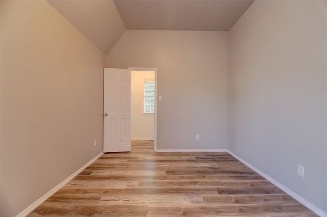 spare room with wood finished floors, baseboards, and lofted ceiling