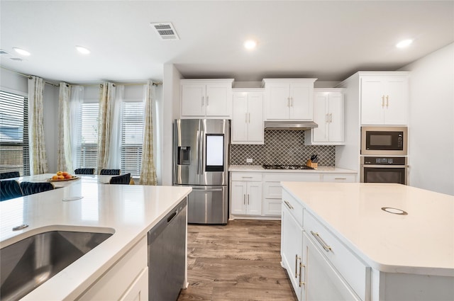 2507 Henley Way, Mansfield, TX 76084 - kitchen featuring black appliances, under cabinet range hood, light wood-style floors, backsplash, and light countertops