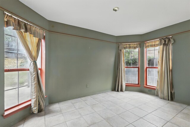 spare room with light tile patterned floors and baseboards