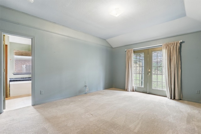 carpeted spare room featuring vaulted ceiling and baseboards