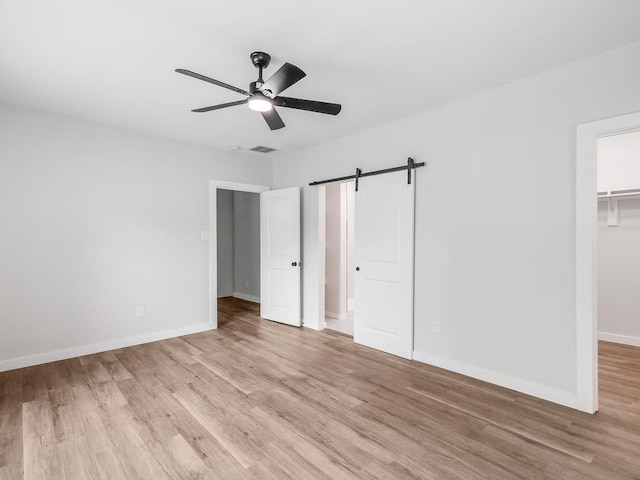 610 SW 3rd St, Kerens, TX 75144 - unfurnished bedroom with light wood-style flooring, a barn door, a spacious closet, baseboards, and a closet