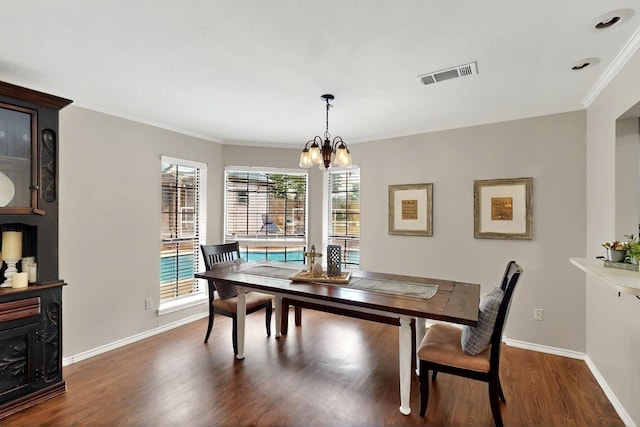 dining room featuring wood finished floors, a chandelier, baseboards, and crown molding